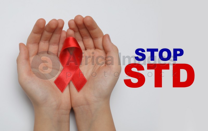 Young woman holding red awareness ribbon on white background, top view. Stop STD 