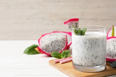 Glass of tasty pitahaya smoothie with fresh mint on white wooden table, space for text