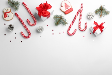 Flat lay composition with candy canes and Christmas decor on white background. Space for text