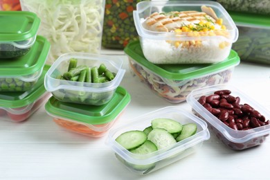 Set of plastic containers with fresh food on white wooden table