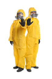 Man and woman in chemical protective suits making stop gesture on white background. Virus research