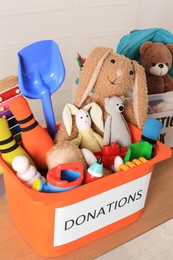Donation box with different child toys on wooden table
