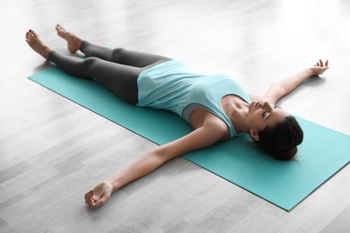Photo of Young woman practicing corpse asana in yoga studio. Savasana pose