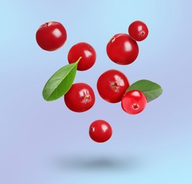 Image of Delicious ripe cranberries and fresh leaves falling on pale light blue background