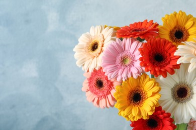 Bouquet of beautiful colorful gerbera flowers on light blue background. Space for text