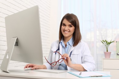 Pediatrician working with computer at table in clinic