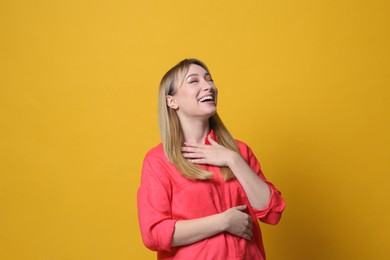 Beautiful young woman laughing on yellow background. Funny joke