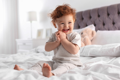 Photo of Cute little child sitting on bed at home