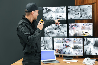Security guard with portable transmitter monitoring modern CCTV cameras indoors