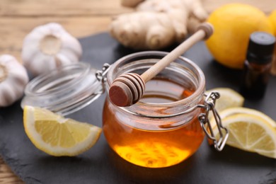 Photo of Cold remedies. Jar of honey and lemon on slate plate, closeup. Cough treatment