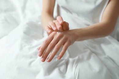 Woman applying hand cream in bed, closeup