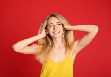Portrait of beautiful young woman with blonde hair on red background