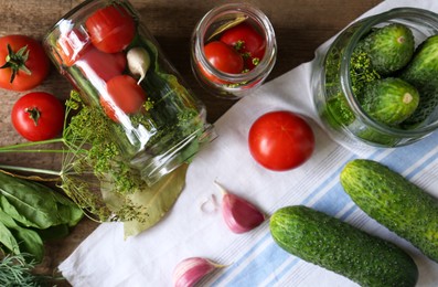 Glass jars, fresh vegetables and herbs on wooden table, flat lay. Pickling recipe