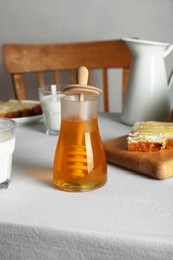 Photo of Delicious honey, milk and bread with butter served for breakfast on table indoors
