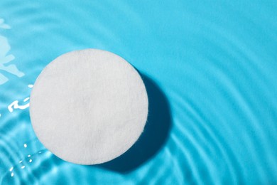 Cotton pad and micellar water on light blue background, top view. Space for text