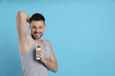 Handsome man applying deodorant on turquoise background. Space for text