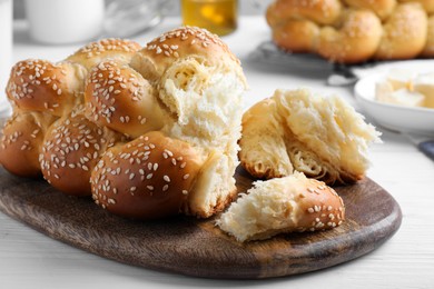 Homemade braided bread with sesame seeds on white wooden table, closeup. Traditional challah