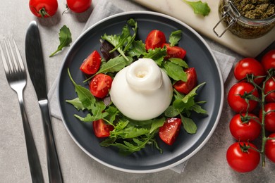 Delicious burrata salad with tomatoes and arugula served on grey table, flat lay