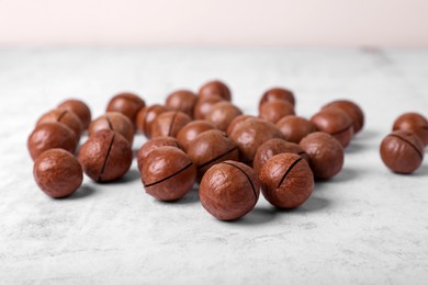 Photo of Delicious organic Macadamia nuts on white textured table, closeup