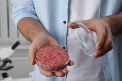 Photo of Scientist holding Petri dish with raw cultured meat in laboratory, closeup