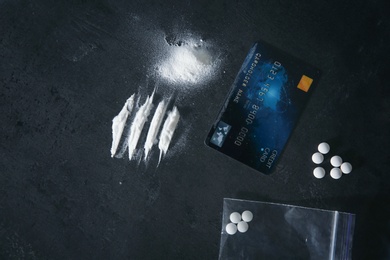 Different drugs and credit card on dark background, flat lay