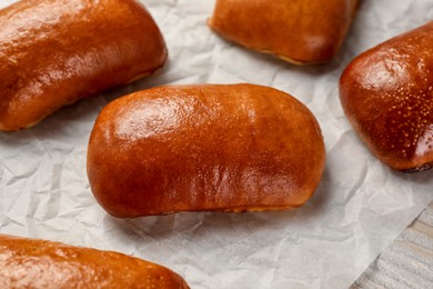 Delicious baked pirozhki on parchment paper, closeup