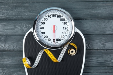 Scales and measuring tape on wooden background, top view. Weight loss