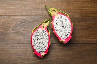 Halves of delicious dragon fruit (pitahaya) on wooden table, flat lay