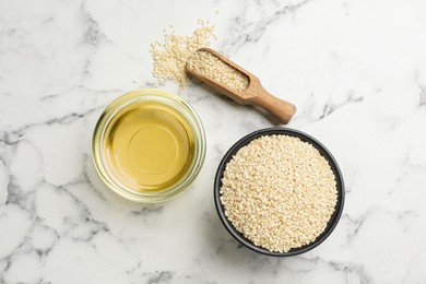 Fresh sesame oil and seeds on white marble table, flat lay
