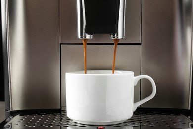 Modern espresso machine pouring coffee into cup, closeup