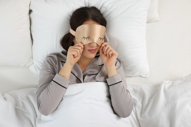 Young woman with sleeping mask in bed, top view. Problem of sleep deprivation