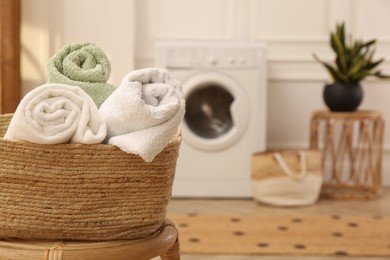 Basket with clean rolled towels on stool in laundry room. Space for text