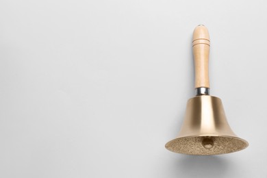 Golden school bell with wooden handle on grey background, top view. Space for text