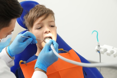 Professional dentist working with little boy in clinic. Space for text