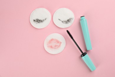 Dirty cotton pads and mascara on light pink background, flat lay