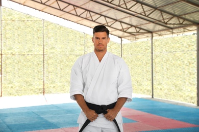 Karate coach wearing kimono and black belt at outdoor gym