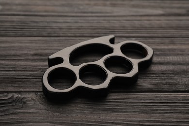Brass knuckles on black wooden background, closeup