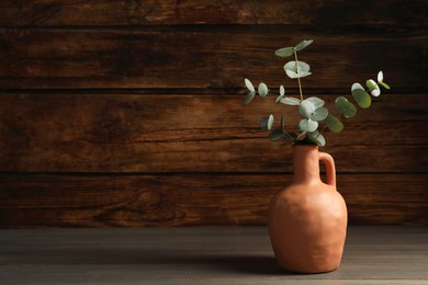 Beautiful eucalyptus branches in vase on wooden table indoors, space for text