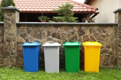 Photo of Many colorful recycling bins near stone fence outdoors
