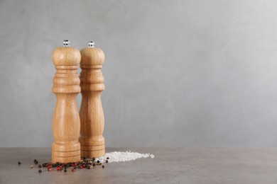 Wooden salt and pepper shakers on grey table, space for text. Spice mill