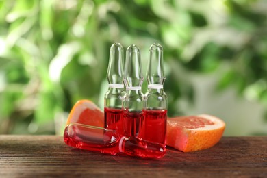 Pharmaceutical ampoules with medication and grapefruit slices on wooden table, closeup