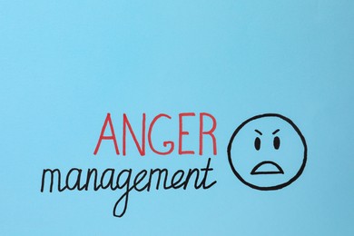 Photo of Words Anger Management and angry face on light blue background. Space for text