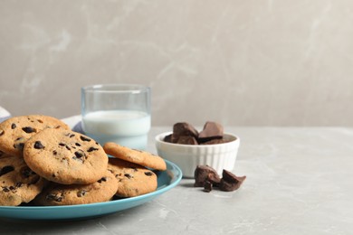 Plate with delicious chocolate chip cookies on grey marble table. Space for text