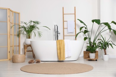 Stylish bathroom interior with modern ceramic tub and beautiful houseplants