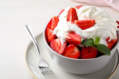 Delicious strawberries with whipped cream served on white wooden table, closeup
