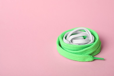 Mint and white shoe laces on light pink background. Space for text
