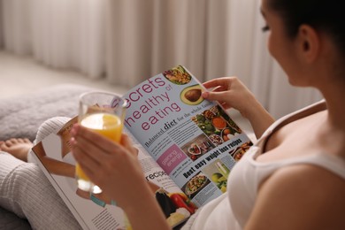 Young woman reading magazine on bed indoors