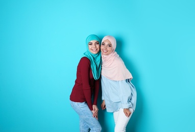 Portrait of young Muslim women in hijabs against color background