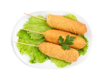 Delicious deep fried corn dogs with lettuce and parsley on white background, top view
