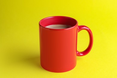 Red mug of freshly brewed hot coffee on yellow background